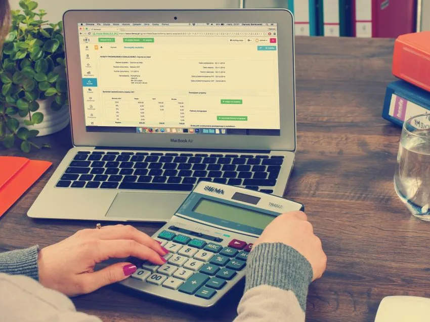 Persona usando una calculadora frente a un notebook con planillas